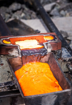 Orange molten metal being poured on dice to weld rail