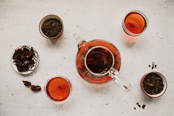 Different types of tea. Black, green and hibiscus sorts on a white table with teapot and glasses. © Edalin