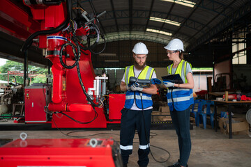 Both of engineers installing and testing a large robotic arm. before sending it to customers for use in the industry