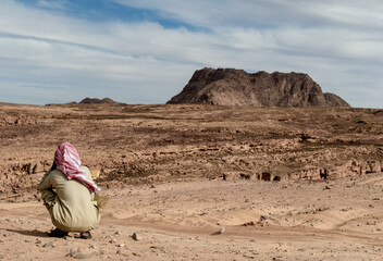 lonely bedouin sits and waits in the desert in egypt