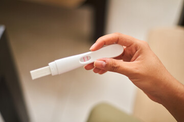Close up of young latina woman looking at positive pregnancy test. Concept, conscious motherhood, family planning. - obrazy, fototapety, plakaty
