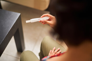 Close up of young latina woman looking at positive pregnancy test. Concept, conscious motherhood, family planning.