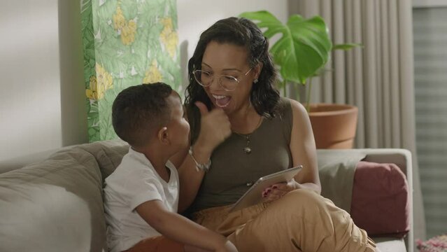 Latina mother cute little preschool son at home play on wireless tablet device. Smiling mom small kid boy look at pad screen have fun together use modern electronic tech concept
