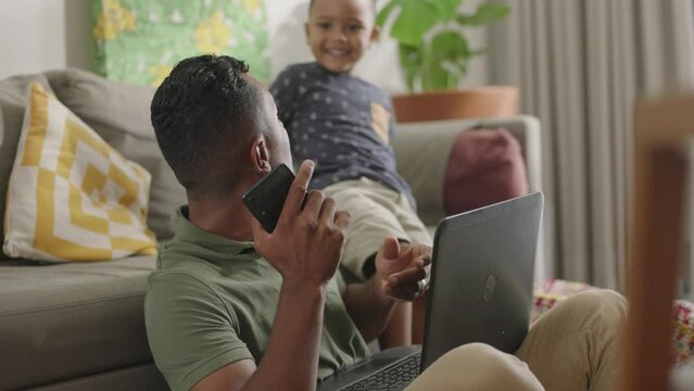 Man working from home with laptop. Home office and parenthood at the same time. Exhausted parent with hyperactive child. Chaos with kids at home

