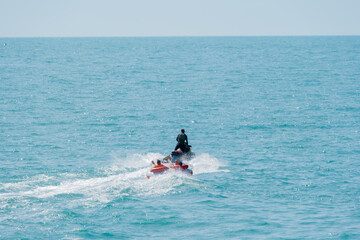 Entertainment at sea, riding on an inflatable boat tied to a jet ski