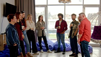 A group of diverse people stand in the middle of the room and talk about something. Business partners hold a meeting in an informal setting.