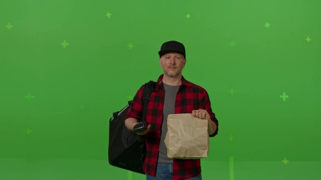 Caucasian male courier passing a box of pizza on green screen chroma key background. Man hold wireless bank payment POS terminal to process acquire credit card payment. Copy space mock up advertising