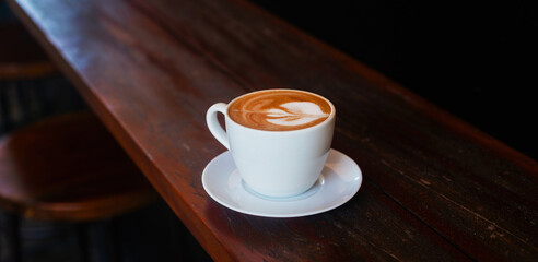 Cappuccino with beautiful foam in a mug on a wooden background. Atmospheric photo of coffee on a dark background