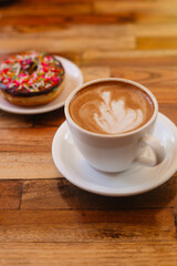 Cappuccino with beautiful foam and donut on a wooden background. Coffee with vegetable milk with dessert for breakfast