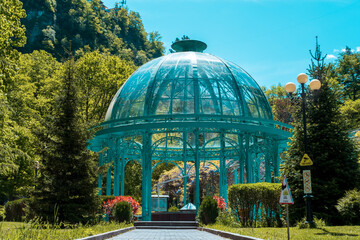 Fototapeta na wymiar Source with healing mineral water. Beautiful pavilion with a glass dome in Borjomi Central Historical Park. Georgia.