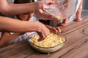 Close up female hands cooking pie. Little girl helps her mother to cook sweet cheesecake.