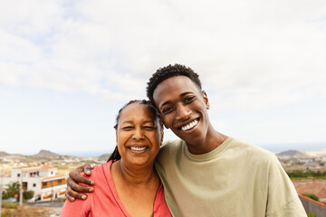 Happy African grandson hugging her grandmother at house rooftop - 611387908