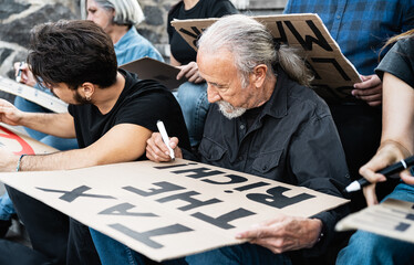 Diverse activists with different age and ethnicity preparing protest banners against financial crisis and global inflation