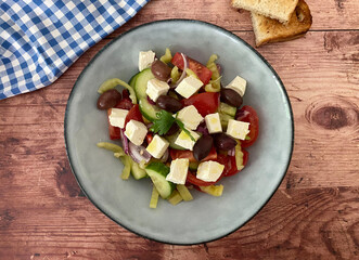 Vegetarian Greek salad with feta cheese, olives, tomatoes, cucumber, peppers, red onions, herbs, marinated with olive oil and lemon juice.