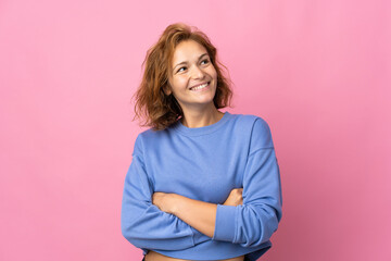 Fototapeta premium Young Georgian woman isolated on pink background looking up while smiling