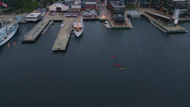 Aerial View of Kayakers Paddling the City Pier Shoreline in Halifax, Canada. Lot of Kayaks Floating on the Ocean off the Coast of the City in the Evening at Dusk.