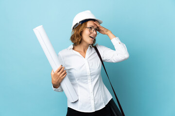 Young architect Georgian woman with helmet and holding blueprints over isolated background has realized something and intending the solution