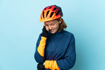 Young cyclist woman isolated on blue background laughing