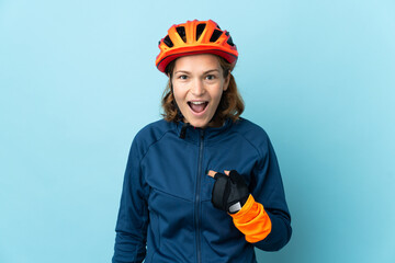 Young cyclist woman isolated on blue background with surprise facial expression