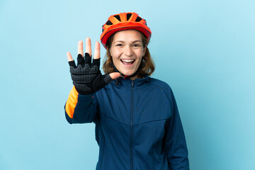 Young cyclist woman isolated on blue background counting five with fingers