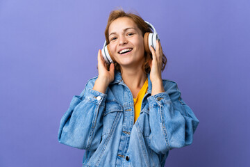Young Georgian woman isolated on purple background listening music