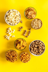 Many bowls with different salty snacks - chips pretzels nuts