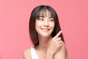 Young Beautiful Asian woman smile with clean and fresh skin Happiness and cheerful with positive emotional pointing up,isolated on pink background,Beauty Cosmetics and spa Treatment Concept