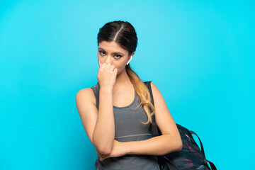 Young sport Russian girl with sport bag isolated on blue background having doubts