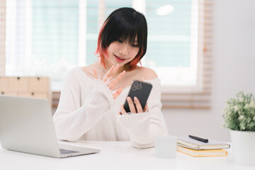 In a cozy living room at home, a beautiful young woman engrossed in messaging on her smartphone...