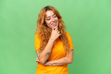 Young caucasian woman isolated on green screen chroma key background looking to the side and smiling