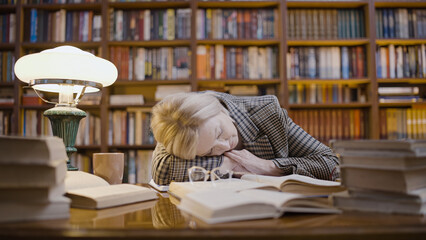 Woman falling asleep after working late in the library, an overworked scientist
