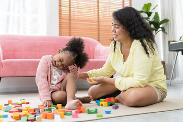 Mother and daughter playing with toy at home. Happy African American girl kid playing with mom