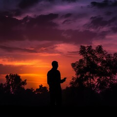 Fototapeta premium Silhouete of a person holding a cell phone outside with sunset