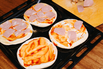 Cooking homemade mini pizza, top view cakes lying on baking sheet