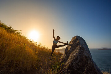 A lady stretching on the hilltop She was admiring the beautiful view of the sea below..She took a deep breath, savoring the moment of peace..On the top of the hill. fresh air
