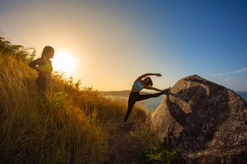 .Two women exercising on the top of a mountain..On the hilltop filled with the smell of the sea,...