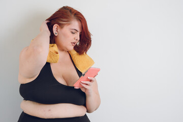 worried young plus size woman reading messages on her phone, on white background, copy space