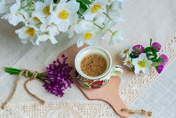 Obraz na płótnie Canvas Coffee with foam and spring wildflowers on a white tablecloth.