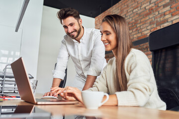 Two business people talking in office using laptop working together