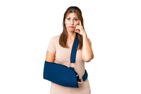 Middle age with broken arm and wearing a sling over isolated background thinking an idea