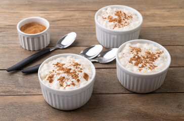 Canjica or munguza, typical brazilian white corn sweet cream with cinnamon over wooden table