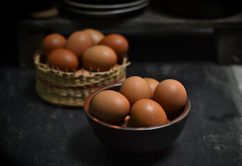 Fresh chicken eggs in a bowl on a wooden board