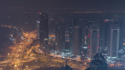 Fototapeta na wymiar JLT and Dubai marina skyscrapers near Sheikh Zayed Road aerial all night timelapse. Residential buildings