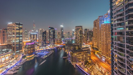 Fototapeta na wymiar Aerial view to Dubai marina skyscrapers around canal with floating boats day to night timelapse