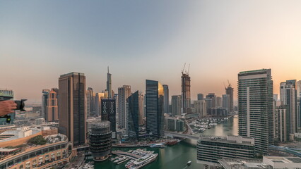 Fototapeta na wymiar Aerial view to Dubai marina skyscrapers around canal with floating boats timelapse
