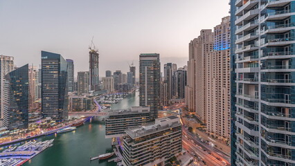 Naklejka premium Aerial view to Dubai marina skyscrapers around canal with floating boats day to night timelapse