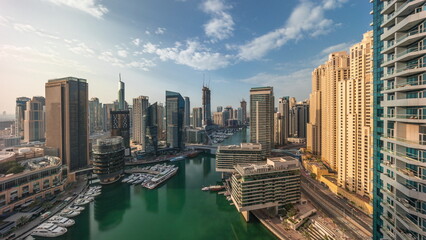 Fototapeta premium Aerial view to Dubai marina skyscrapers around canal with floating boats timelapse