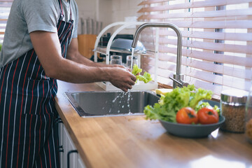 Crop man hand washing lattice with drop of water blur at sink  beside the window in kitchen alone. Healthy food concept, vetgettable or vetgettarian eating oncept.