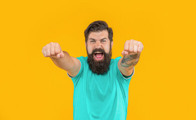 portrait of brutal man with beard shout in studio background isolated on yellow