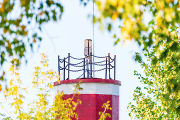 White-Red Lighthouse Surrounded by Green and Yellow Deciduous Trees